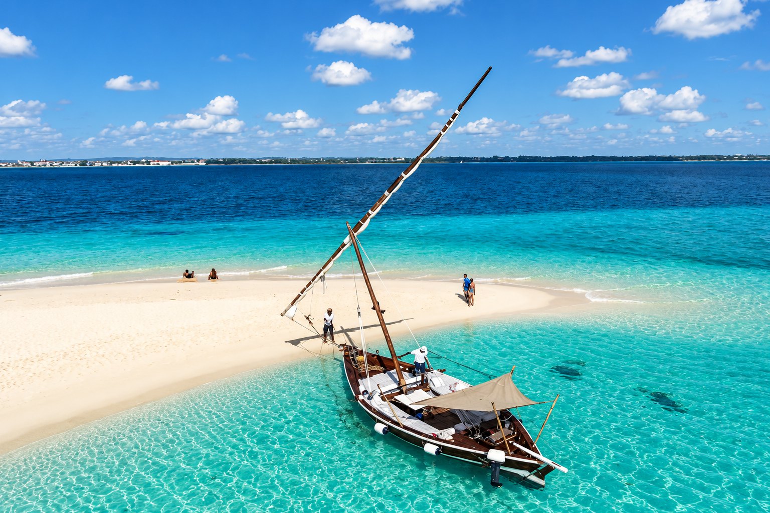 A traditional dhow beside a white sandbar in turquoise ocean water